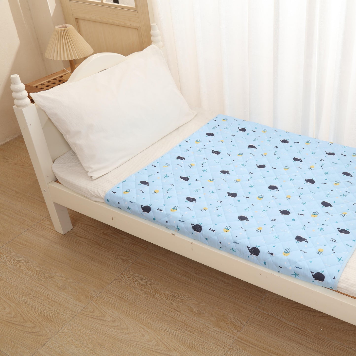 Bed with a blue mattress cover featuring black and yellow polka dots, white pillow, and wooden floor.