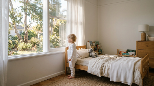 Toddler in pyjamas standing at bedroom window at sunrise - when to stop using pull-ups at night, Rudie Baby Australia