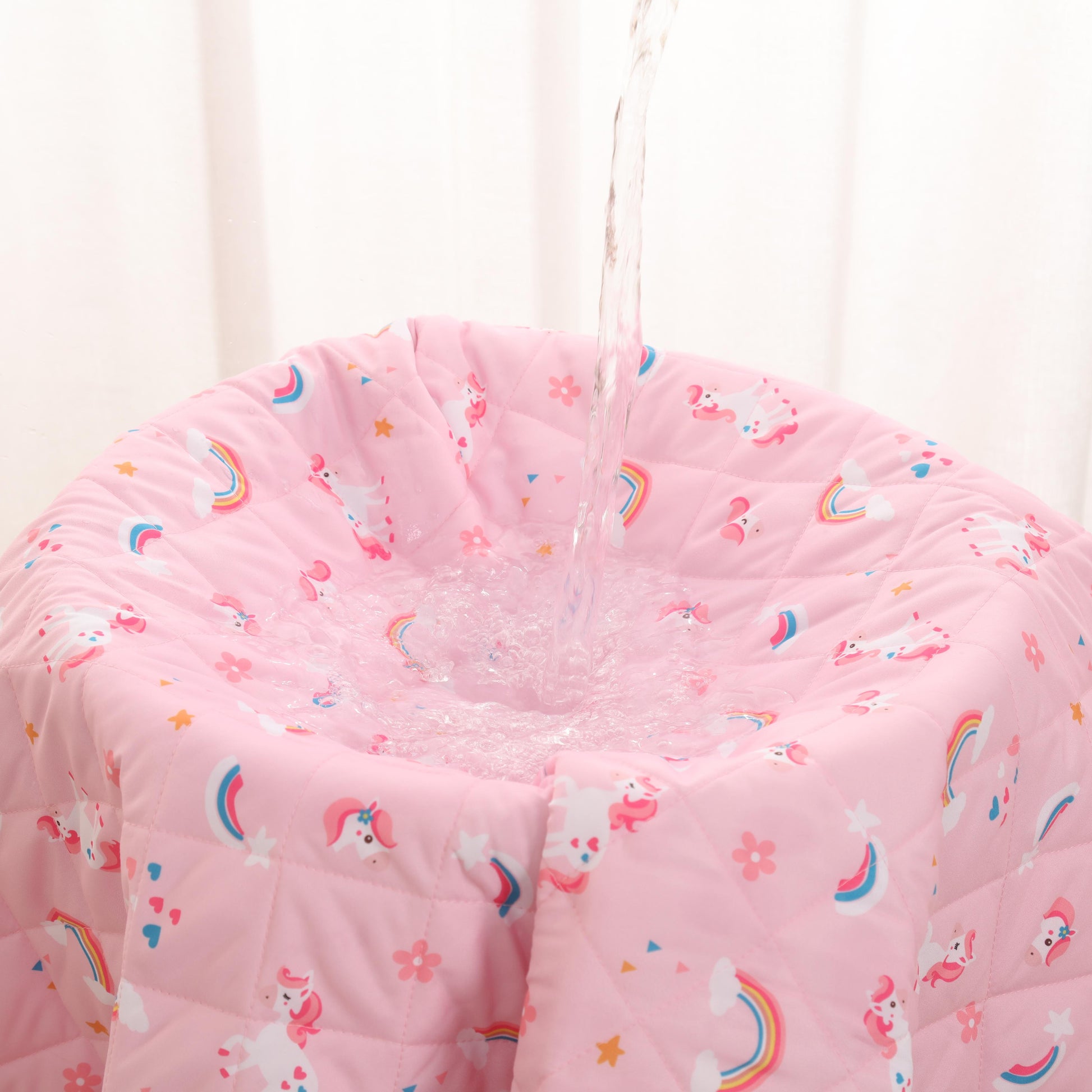 bed wetting blanket with unicorn and rainbow pattern against a white curtain background